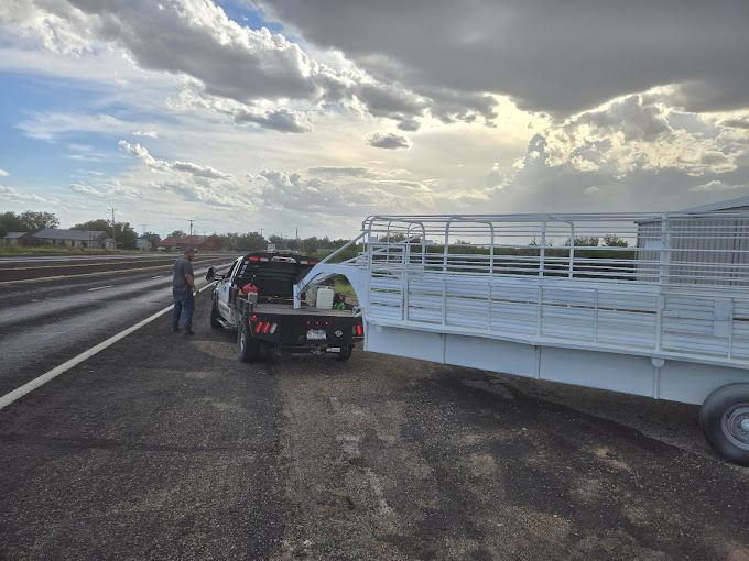 A truck with a trailer attached to it on the side of the road