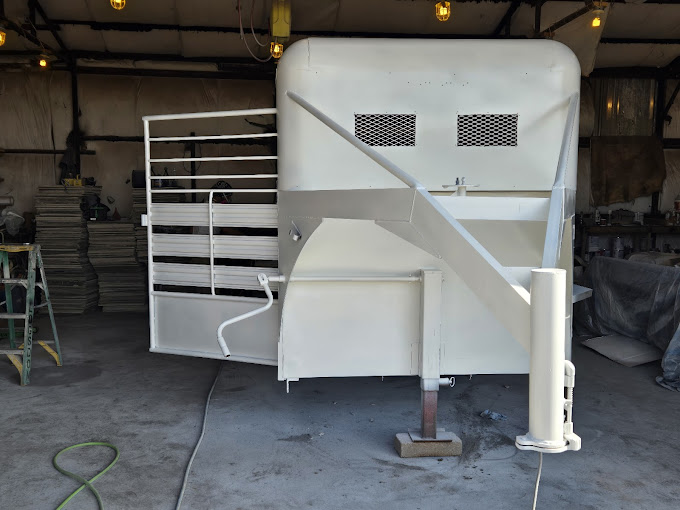 A white horse trailer sitting in a garage