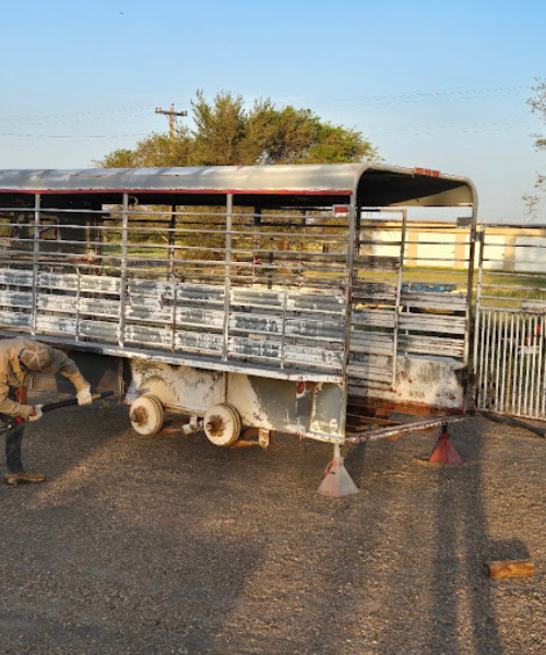 A man working on a cattle trailer in a parking lot