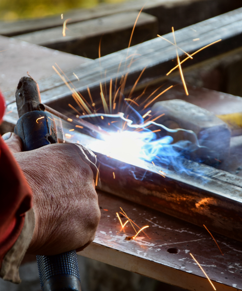 Welder working on a piece of metal with sparks